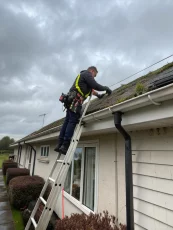 A technician cleaning leaves and debris from a home's gutters using professional equipment, ensuring proper water flow and preventing potential water damage.